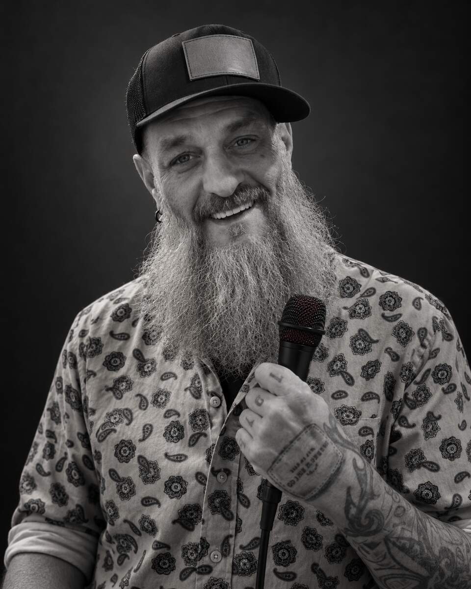 Black-and-white portrait of comedian Jay Cox, The RADneck, holding a microphone.